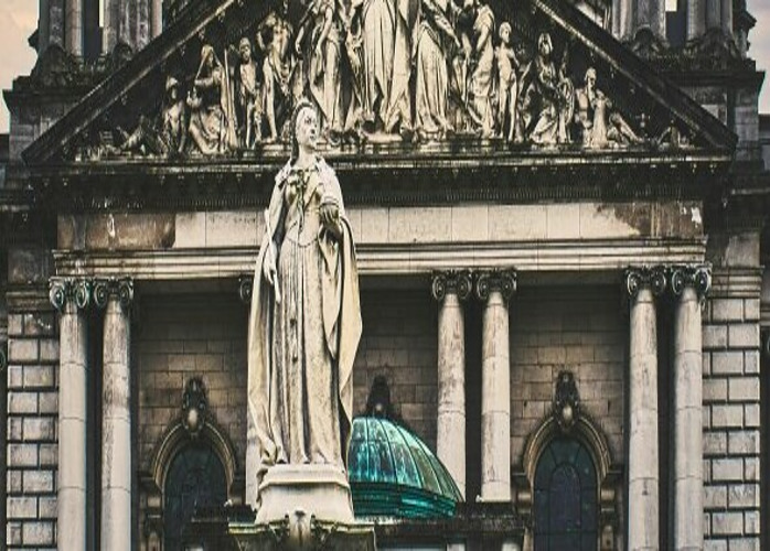 Statue of queen Victoria in front of old stone architecture