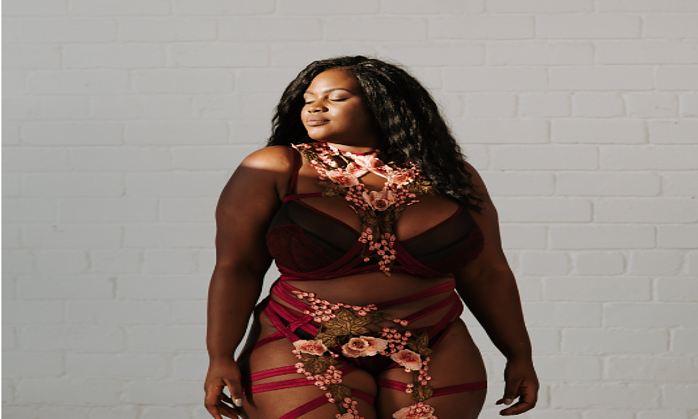 brown-woman-wearing-sexy-burgundy-lingerie-with-her-eyes-closed-florals-tied-around-the-ensemble